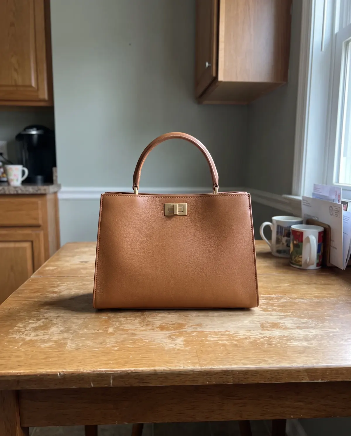 A tan leather handbag photographed on a phone in poor light