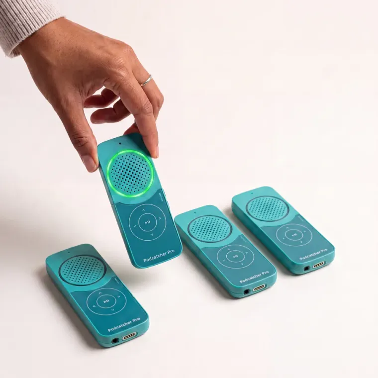 Four Podcatcher Pro devices on a white surface, one lifted by a hand