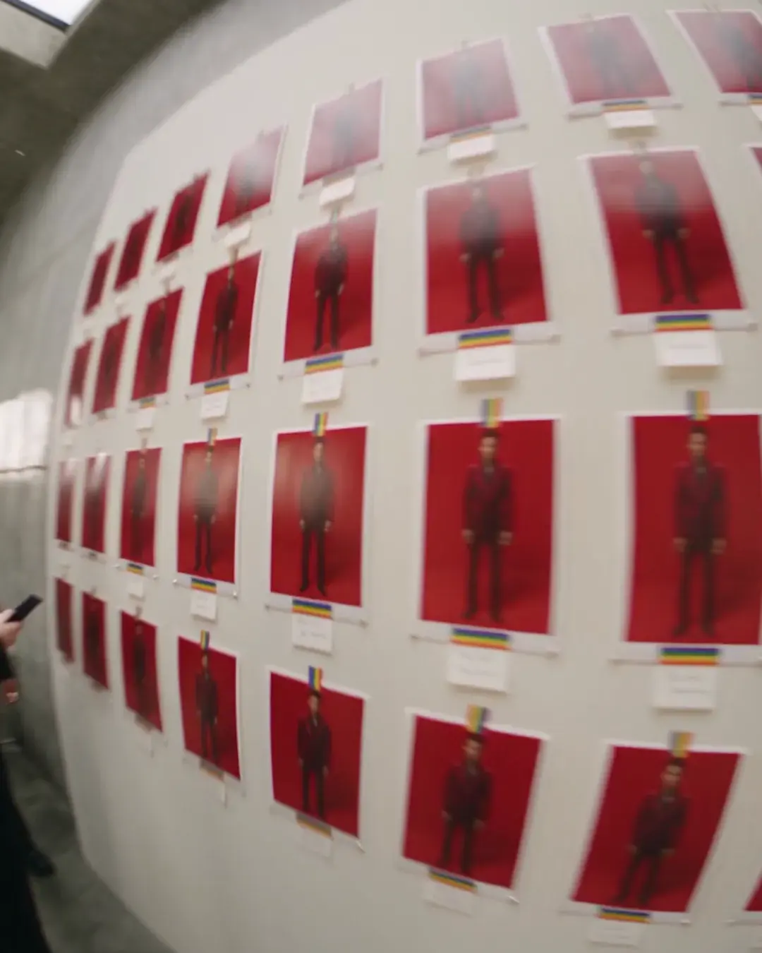 A long curved wall carrying dozens of labelled prints from a single shoot