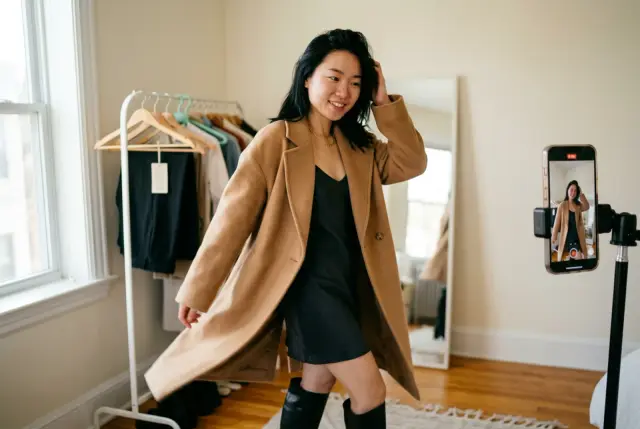 A young woman turning to show a new autumn outfit to a phone on a tripod
